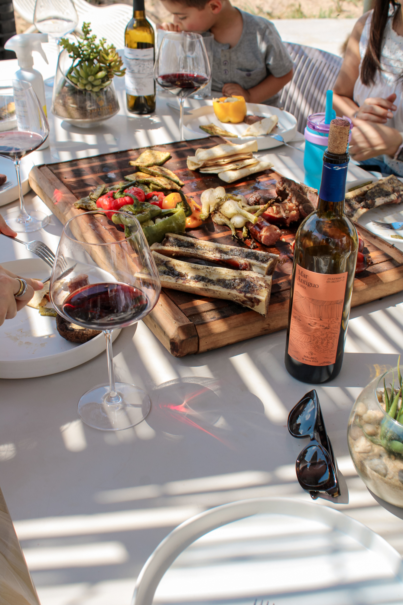 Mesa con tabla de carnes asadas, verduras y vino Mar Antiguo de Sierto